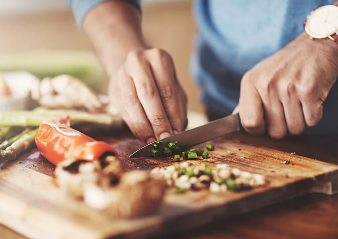 Close up of someone chopping vegetables on a cutting board.